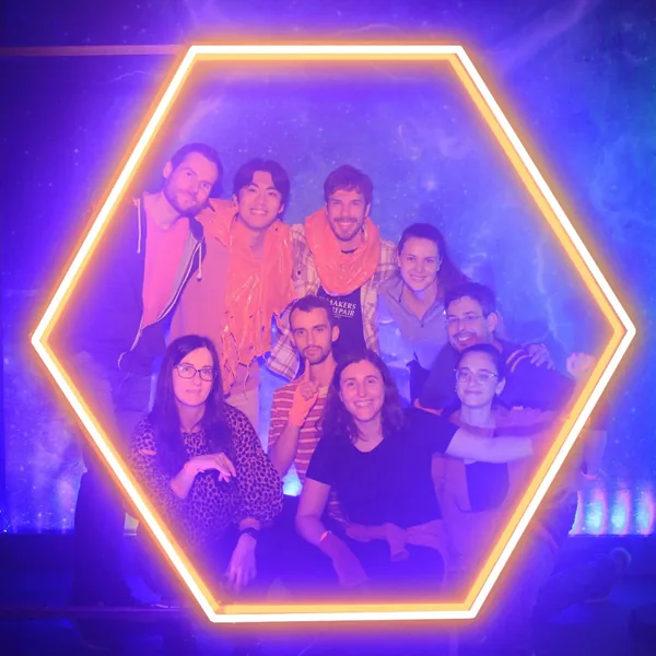 Lab members posing inside a lit hexagonal frame at Secret Cinema, 2022